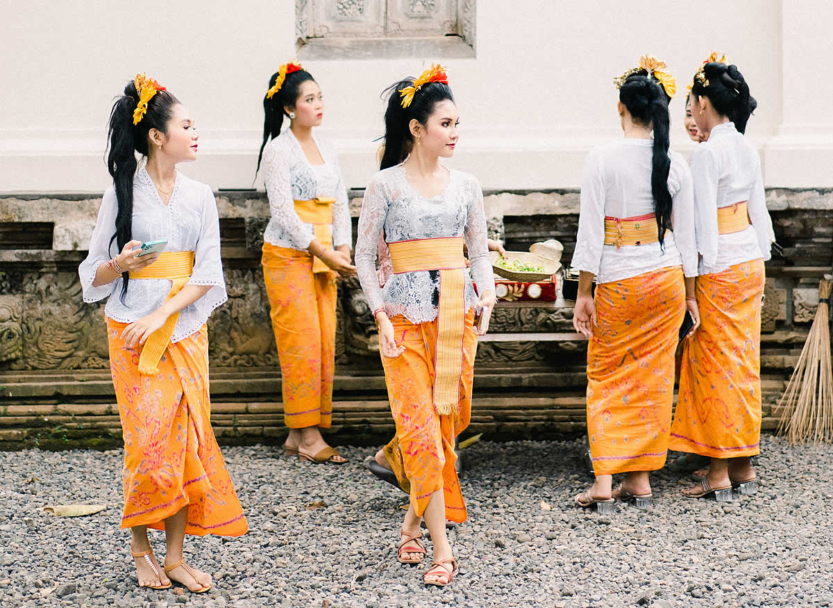 Women in Bali in traditional attire preparing for a cultural dance outdoors | photo